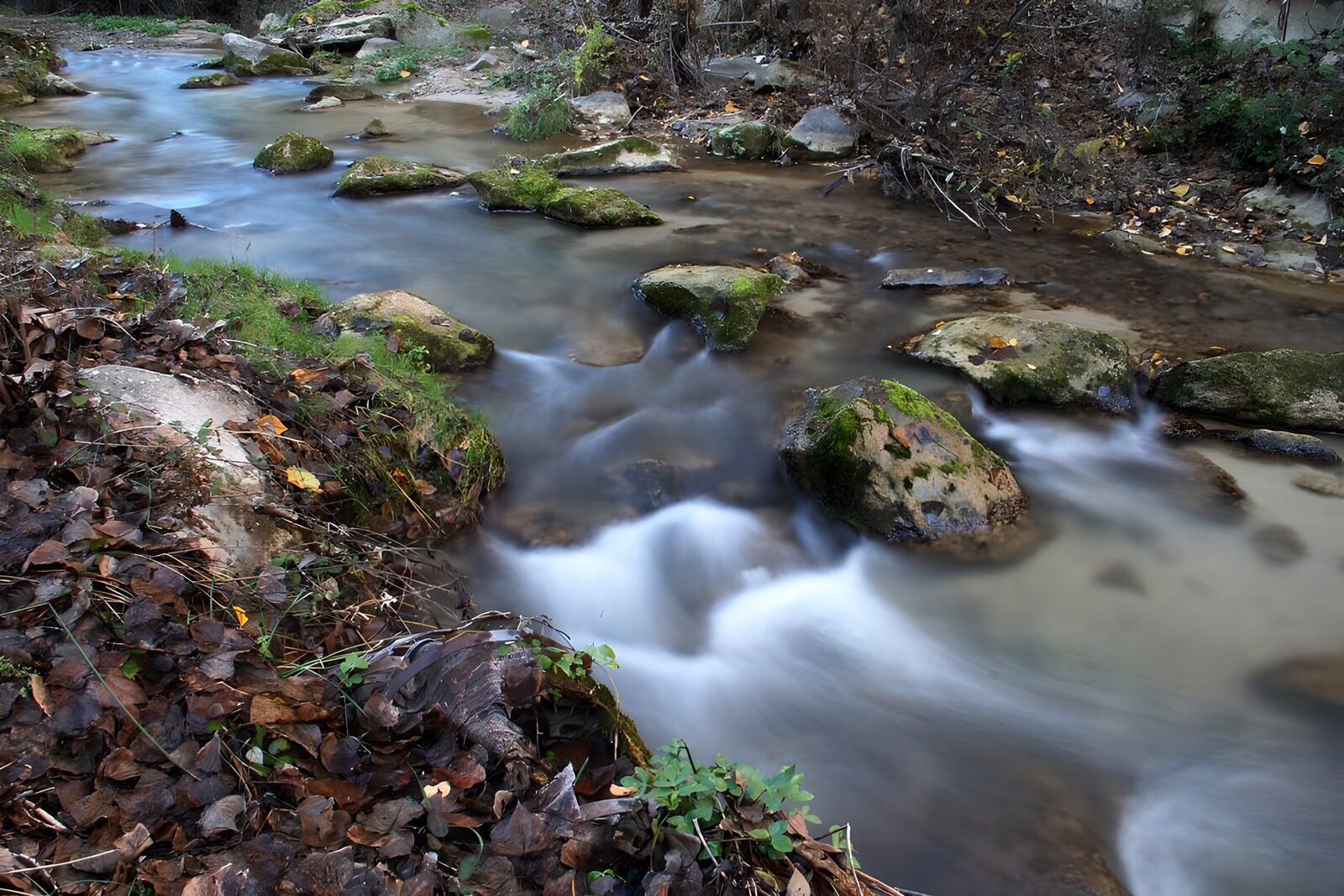 OCCOM3484452: Serene Stream Flowing Through Rocky Terrain