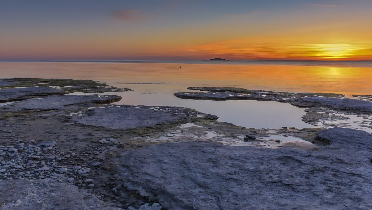 Serene Sunset Over Rocky Shoreline